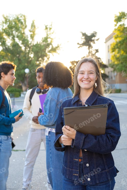 Preview: Smiling college student holding folders on campus