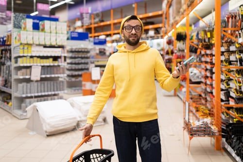 Preview: a confused buyer in a construction hypermarket waving his hands in surprise in bewilderment