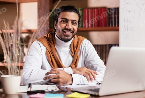 Preview: Successful Indian Teacher Sitting At Laptop Posing In Library Indoors
