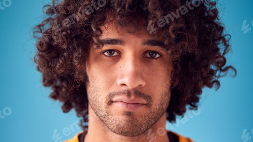 Preview: Portrait Of Confident Man With Serious Expression Looking Into Camera Against Blue Background