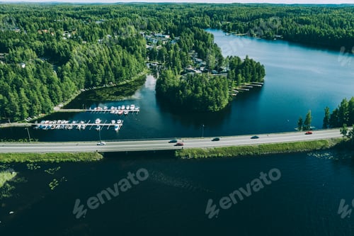 Preview: Aerial view of road with cars over blue lake in Finland. Beautiful summer landscape.