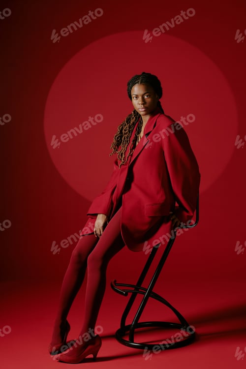 Preview: Sitting Person in Red Suit Against Red Backdrop