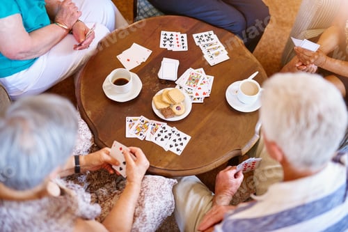 Preview: High angle shot of a group of seniors playing cards around a table in their retirement home