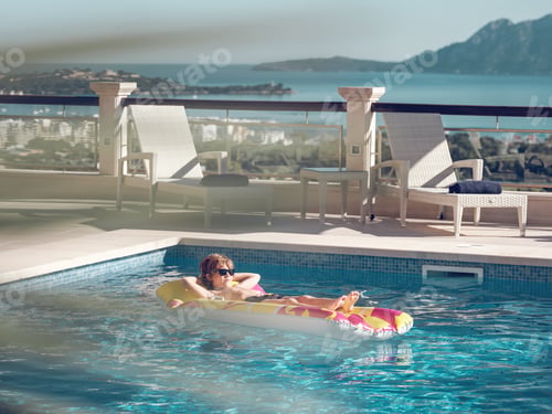 Preview: Boy resting in hotel swimming pool