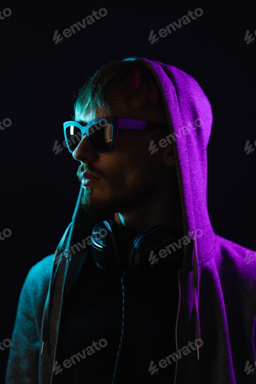 Preview: Portrait of man with headphones on neck in neon lights on dark background