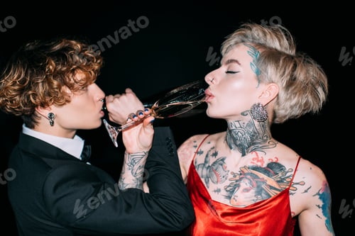 Preview: woman in red dress and man with curly hair drinking champagne isolated on black