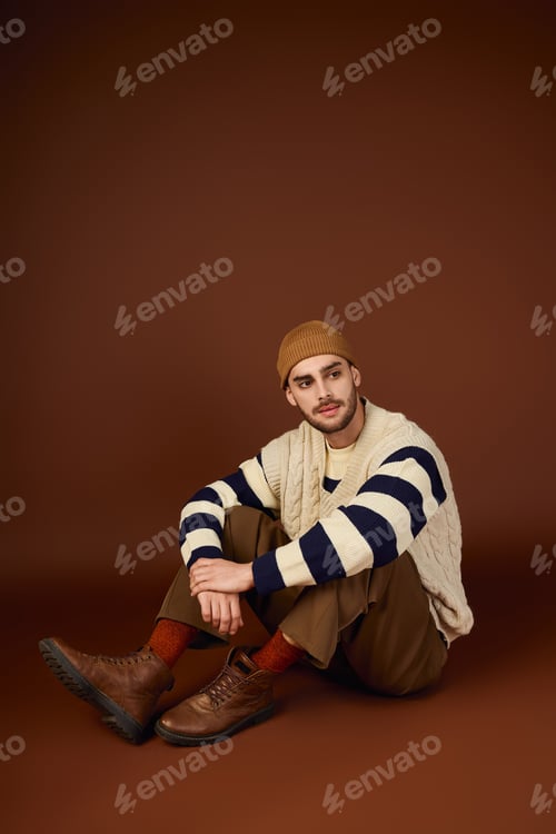 Preview: Stylish young man embraces winter fashion with trendy beanie in studio shoot