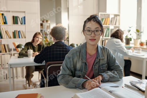 Preview: Asian Woman Wearing Glasses Studying at Desk in School Library
