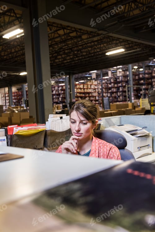 Preview: A caucasian female worker working on a computer problem in a distribution warehouse.