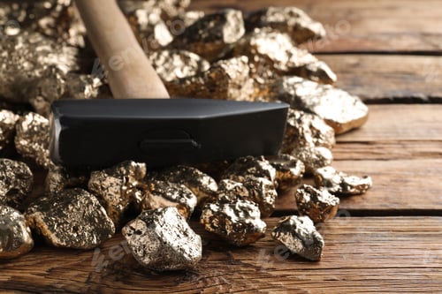 Preview: Pile of gold nuggets and hammer on wooden table, closeup