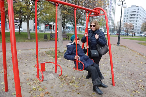 Preview: Two senior ladies enjoying ride on swings in park, elderly friends, retirement