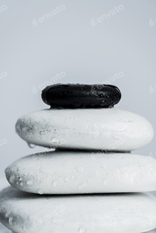 Preview: Macro shot of black and white zen stones in water drops isolated on grey