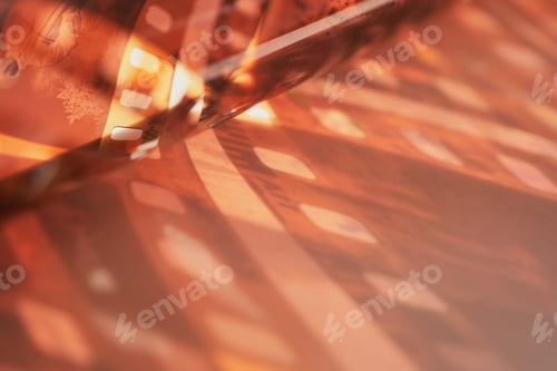 Preview: Orange film negative with sprocket holes creating abstract light and shadow patterns