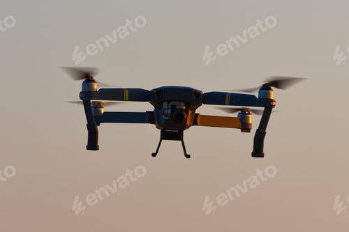 Preview: Drone quad copters with high resolution digital camera flying aerial over sunset orange sky