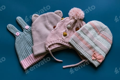Preview: Four different pink knitted hats for a girl for autumn and winter on a blue background