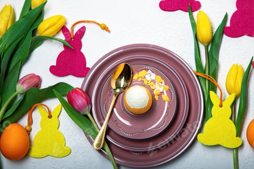 Preview: Easter spring composition with yellow and pink tulips, decorative hares and colored eggs on a white