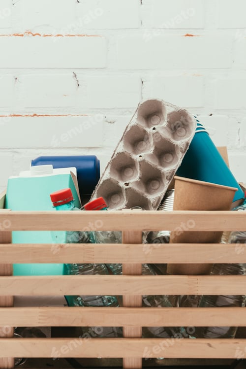 Preview: close up view of various types of trash in wooden box with white brick wall on background