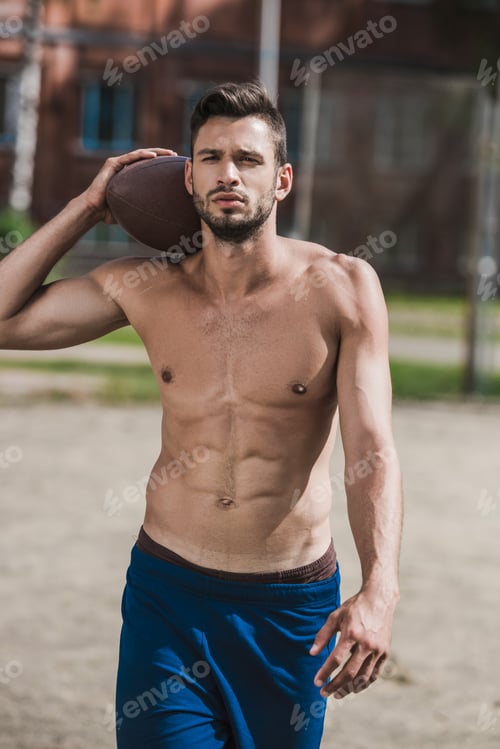 Preview: young handsome male football player with ball on court
