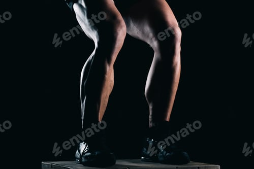 Preview: Studio photo of the lower part of a strong man's legs with black background
