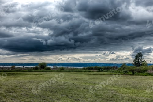 Preview: Dark Storm Clouds Hover Over A Green Meadow In Normany Park, Washington.