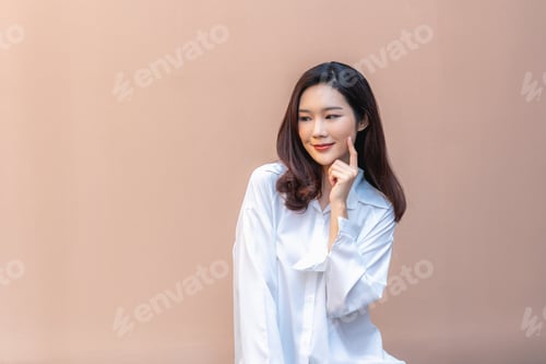 Preview: Pensive Woman in White Shirt Against Peach Background