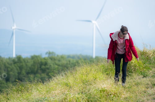 Preview: On the background of windmills, A young woman in a red jacket is enjoying her winter vacation.