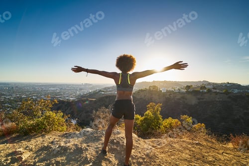 Preview: athletic african american woman celebrating reaching top of runyon canyon with arms open