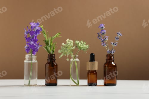 Preview: Different herbs in glass bottles and essential oil on white table against brown background