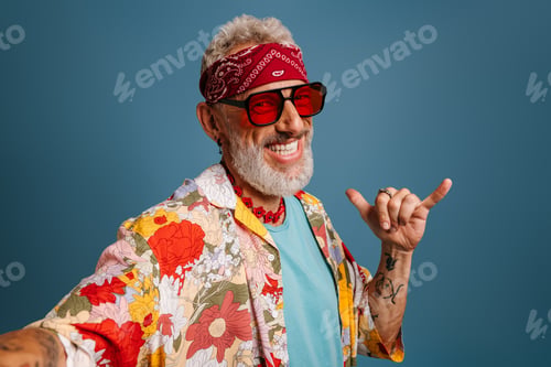 Preview: Hipster senior man in stylish funky shirt and trendy glasses making selfie and gesturing