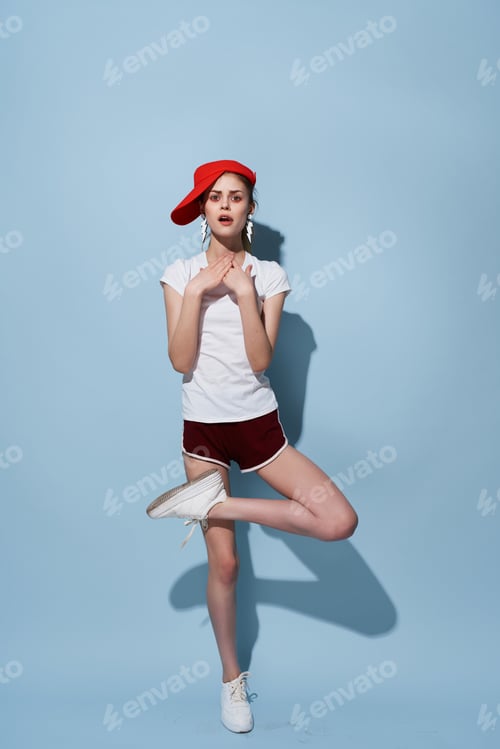 Preview: attractive woman in red cap and shorts posing summer fashion studio