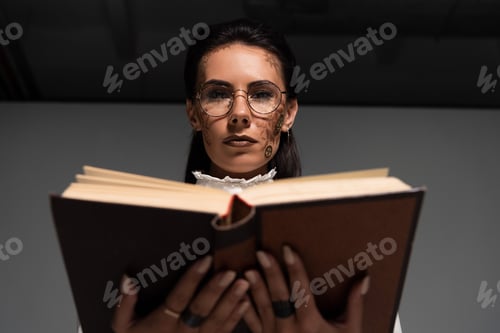 Preview: selective focus of steampunk woman in glasses reading book