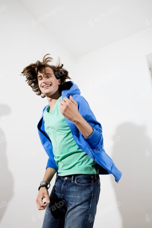 Preview: Germany, Berlin, Young man playing air guitar, smiling, portrait