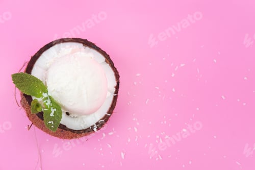 Preview: Vanilla ice cream balls in fresh coconut halves, decorated with mint leaves on a pink background