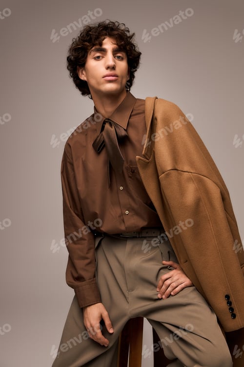 Preview: Handsome young man showcasing unique fashion style with elegance in a studio setting