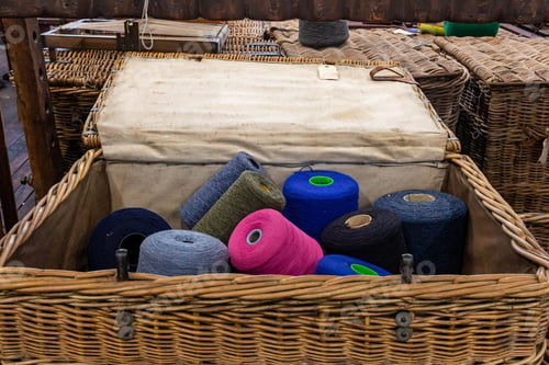 Preview: a basket filled with various colored yarn on a table next to other items