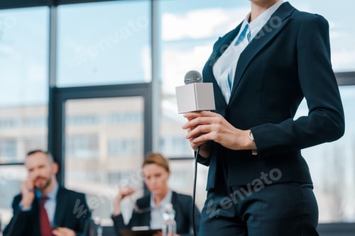 Preview: cropped view of journalist holding microphone while standing near diplomats
