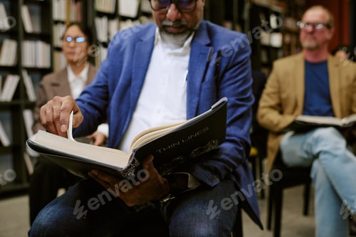 Preview: Middle Aged Man Reading Book during Presentation in Library Setting