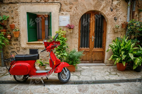 Preview: A vintage red scooter parked near the old house in the European old town