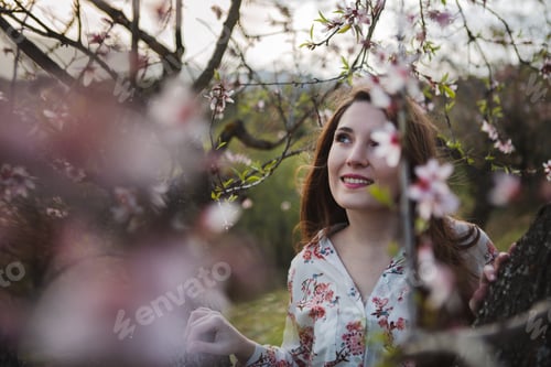 Preview: Young happy woman between trees in garden