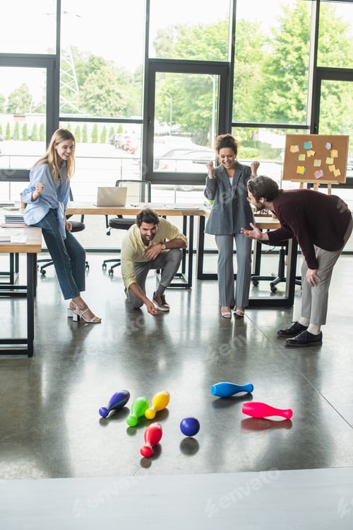 Preview: Multiethnic business people showing yes gesture while playing bowling in office