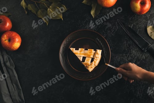 Preview: partial view of female hand holding piece of apple pie on cake server isolated on black marble table