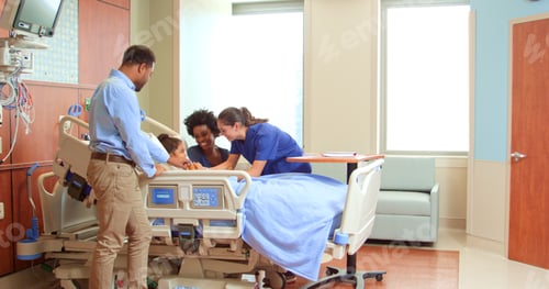 Preview: Female Doctor Or Nurse With Soft Toy Meeting Parents Visiting Daughter In Hospital Bed