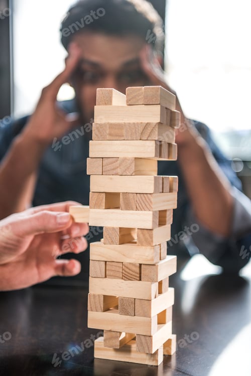 Preview: young friends playing jenga game, focus on foreground