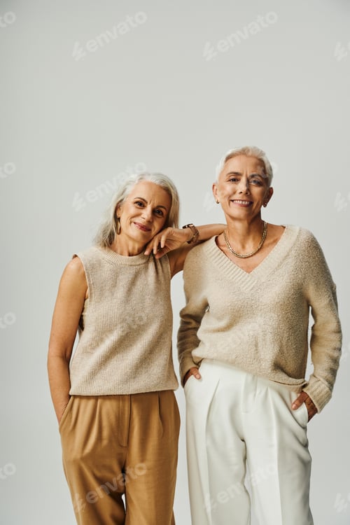 Preview: smiley senior women in stylish pastel attire looking at camera on grey, positivity and charm