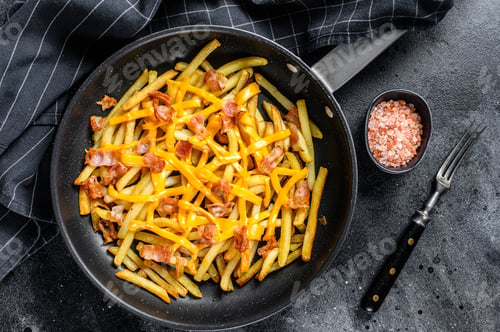 Preview: French fries baked with cheddar cheese and bacon in a pan. Black background. Top view