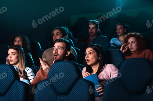 Preview: Group of cheerful people laughing while watching movie in cinema.