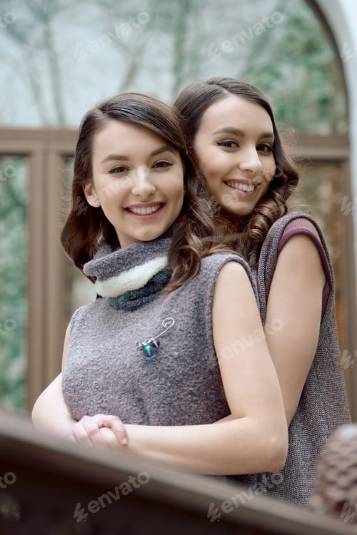 Preview: Two sisters in warm sleeveless dress hug each other