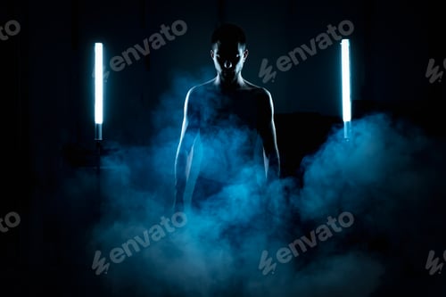 Preview: Portrait of attractive young male model in cinematic backlight on black background without shirt