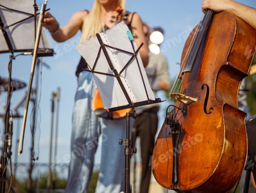 Visualização: Músico com violoncelo sentado perto do suporte de notas musicais