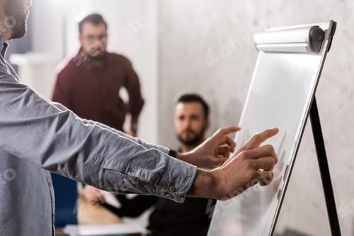 Preview: businessman pointing on something at flipchart in office